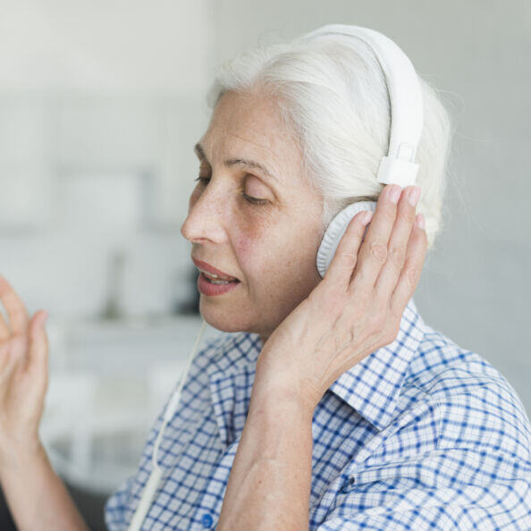 side-view-senior-woman-listening-music-headphone-singing